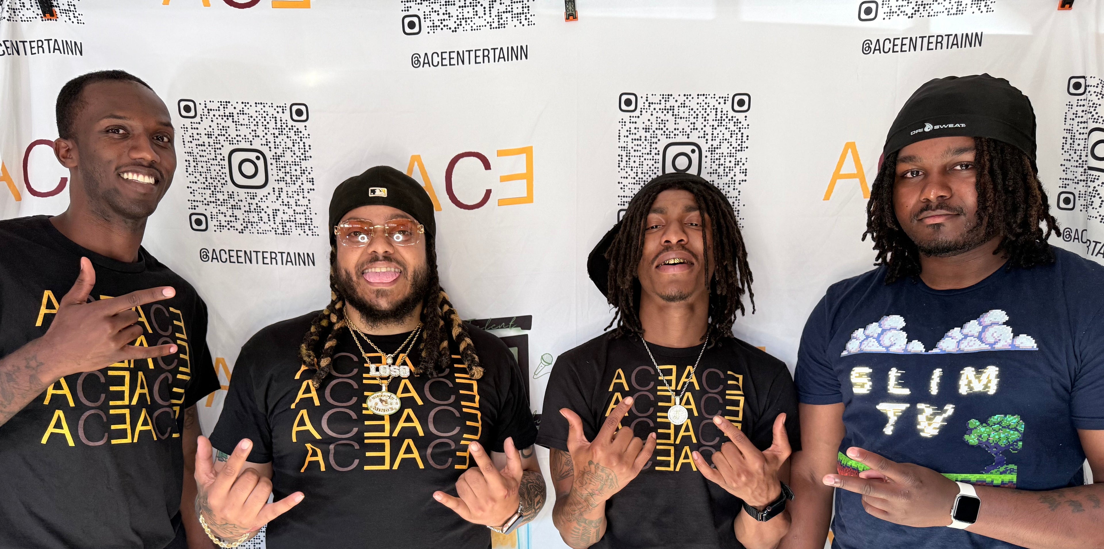 Four men posing together in front of a branded backdrop